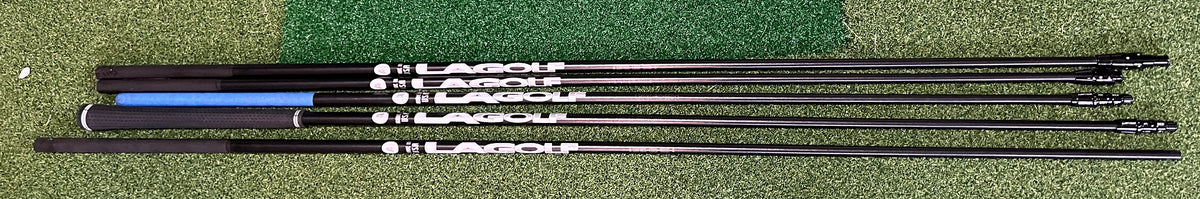 A set of black LA golf shafts with white and blue Larches branding, laid horizontally on a green artificial turf background.